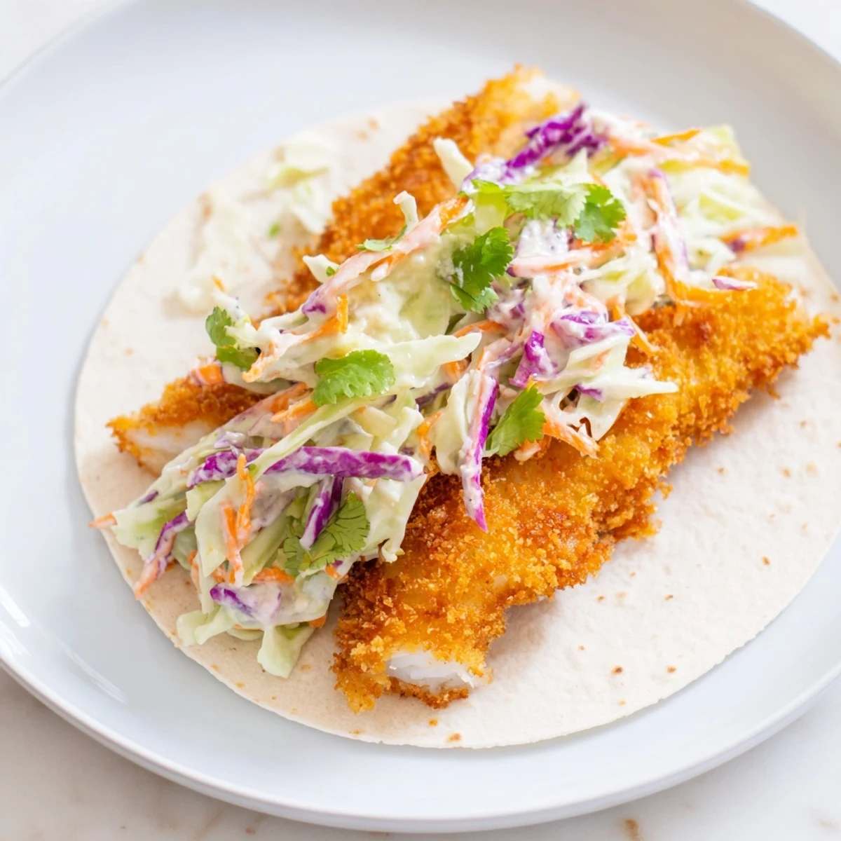 Golden, crispy fish fillets tucked into warm tortillas topped with bright cabbage slaw and creamy sauce.
