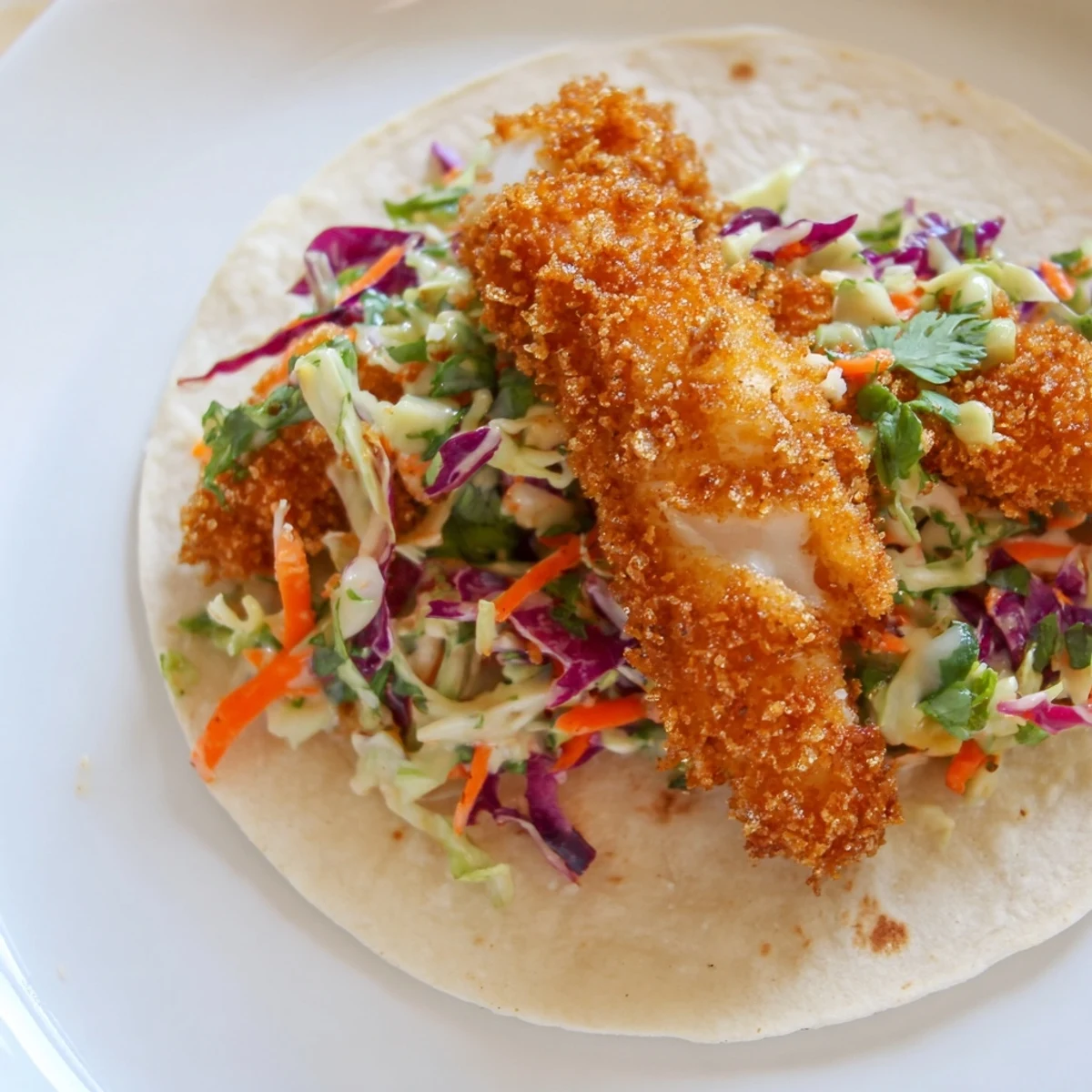 Crispy Fish Tacos with Cabbage Slaw served hot with lime wedges and chopped cilantro on a rustic table.