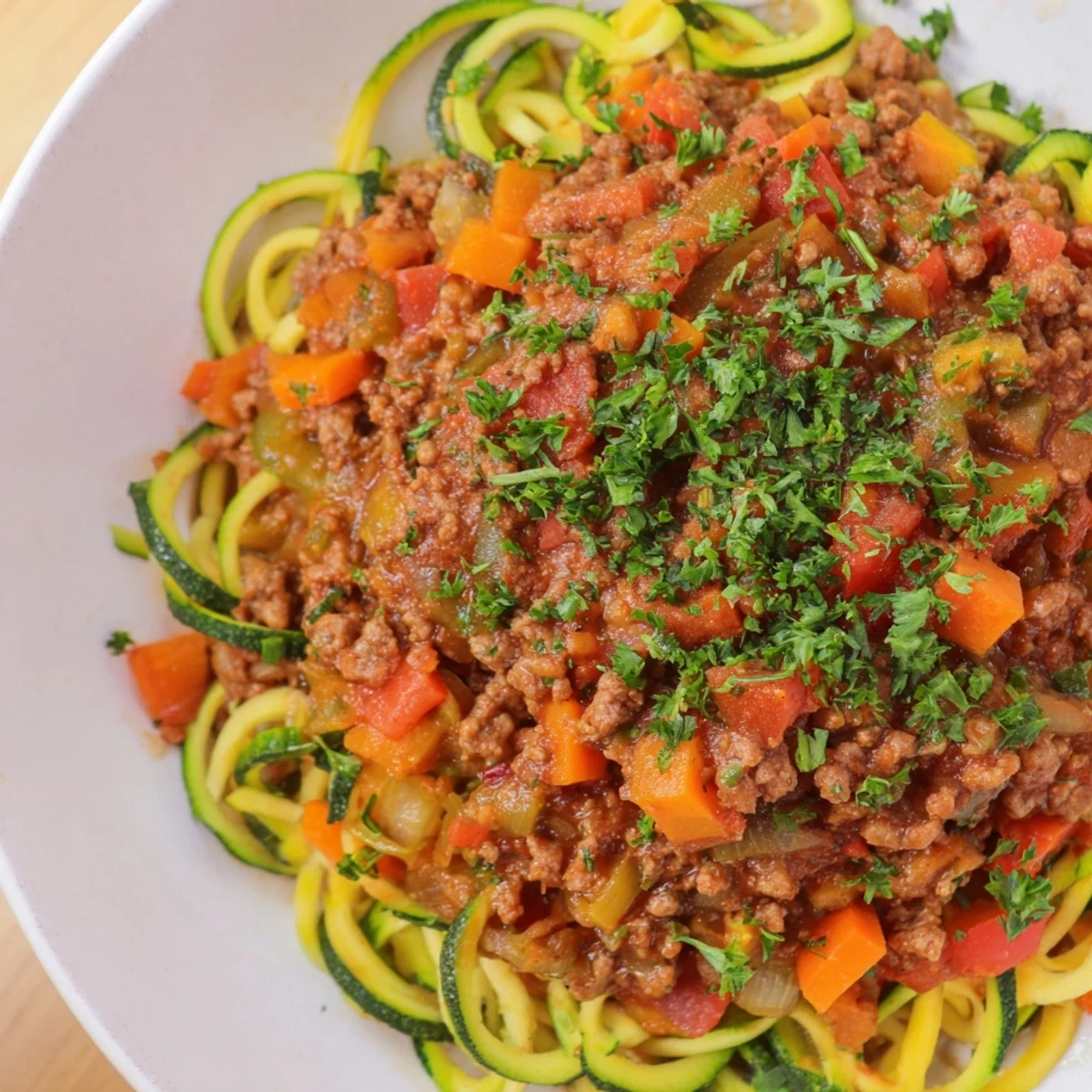 Steaming Turkey Bolognese Sauce with Zucchini Noodles served in a white bowl, garnished with parsley, highlighting a low-carb, gluten-free Italian main dish.