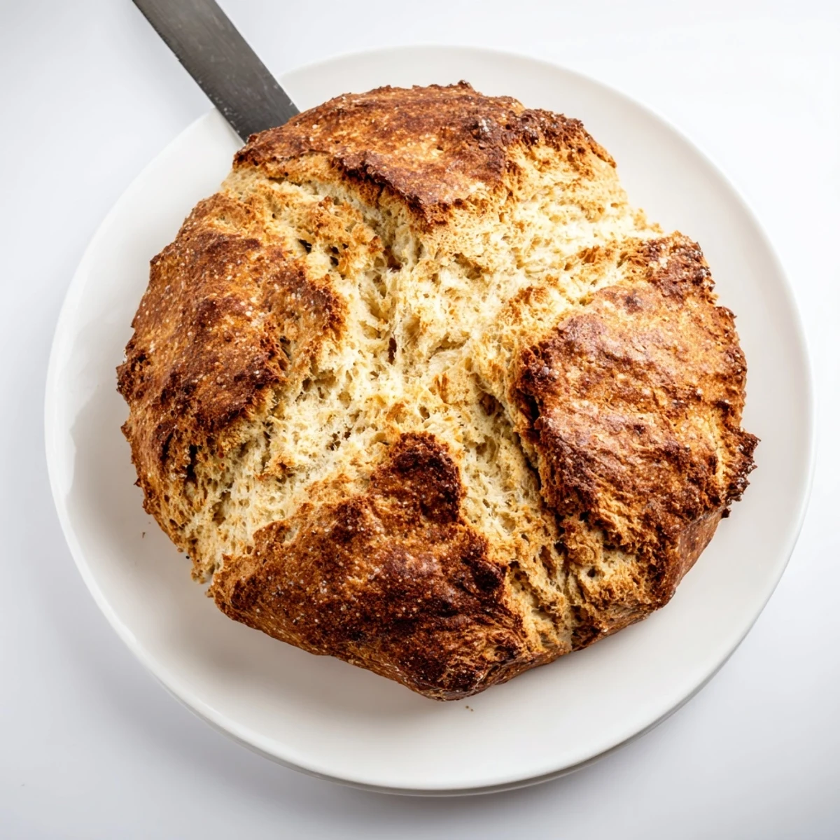 A rustic slice of Authentic 4-Ingredient Irish Soda Bread sits beside a cup of tea, offering a cozy breakfast suggestion.