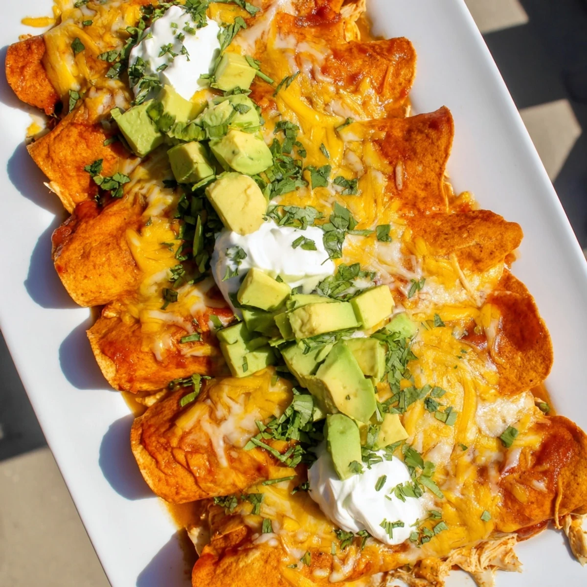 Green Enchiladas With Chicken served hot with a dollop of sour cream, fresh cilantro, and creamy avocado slices for a vibrant Mexican-inspired main dish.