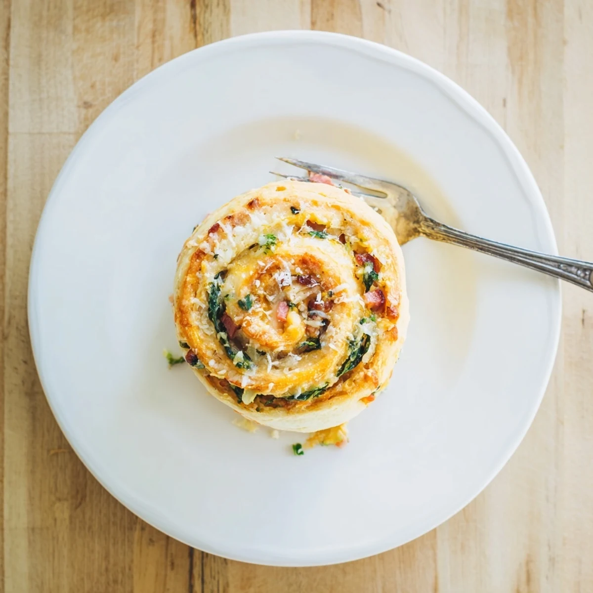 A close-up of a Savory Spinach and Ham Breakfast Roll shows flaky, golden layers with melted cheese and green onions.