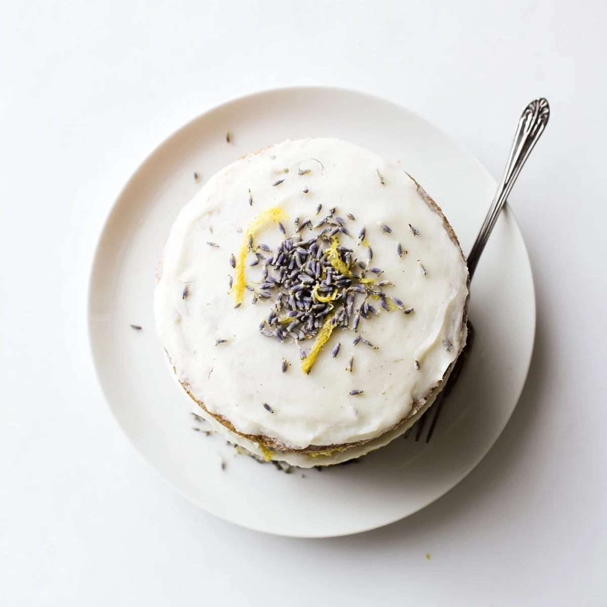 A slice of Earl Grey lavender cake layered with creamy vanilla bean frosting on a white plate.