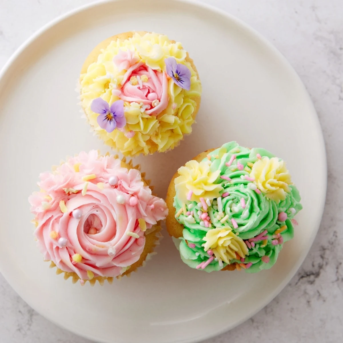 Baby In Bloom Cupcakes decorated with pink and yellow buttercream petals, ready for a spring celebration.