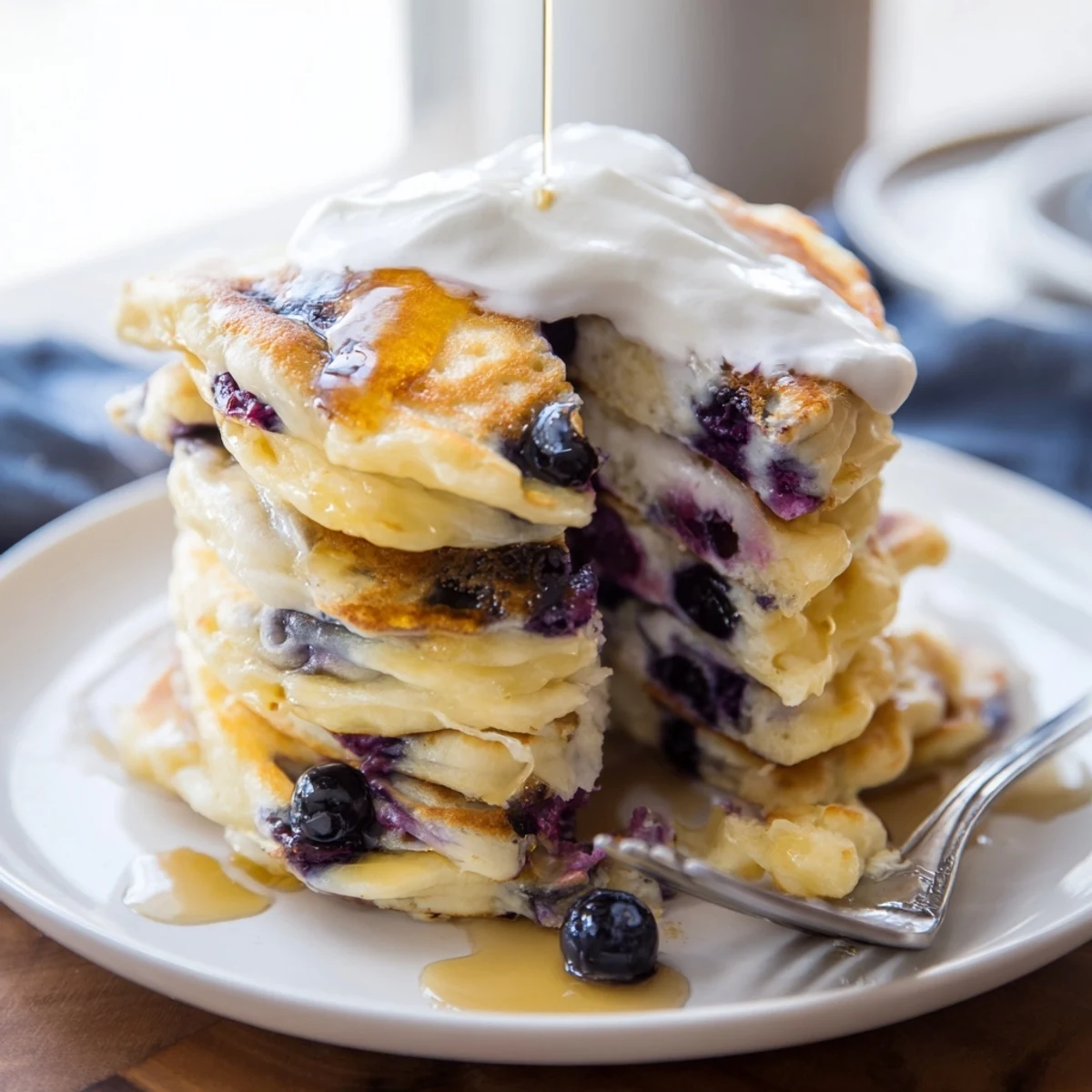 Fluffy American breakfast pancakes with Greek yogurt and juicy blueberries on a white plate