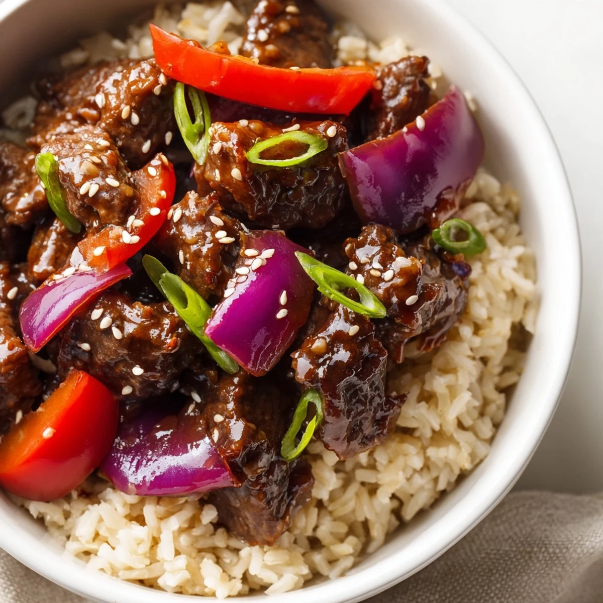 Healthy beef and pepper rice bowl featuring tender beef strips with colorful bell peppers in garlic-ginger sauce over fluffy brown rice