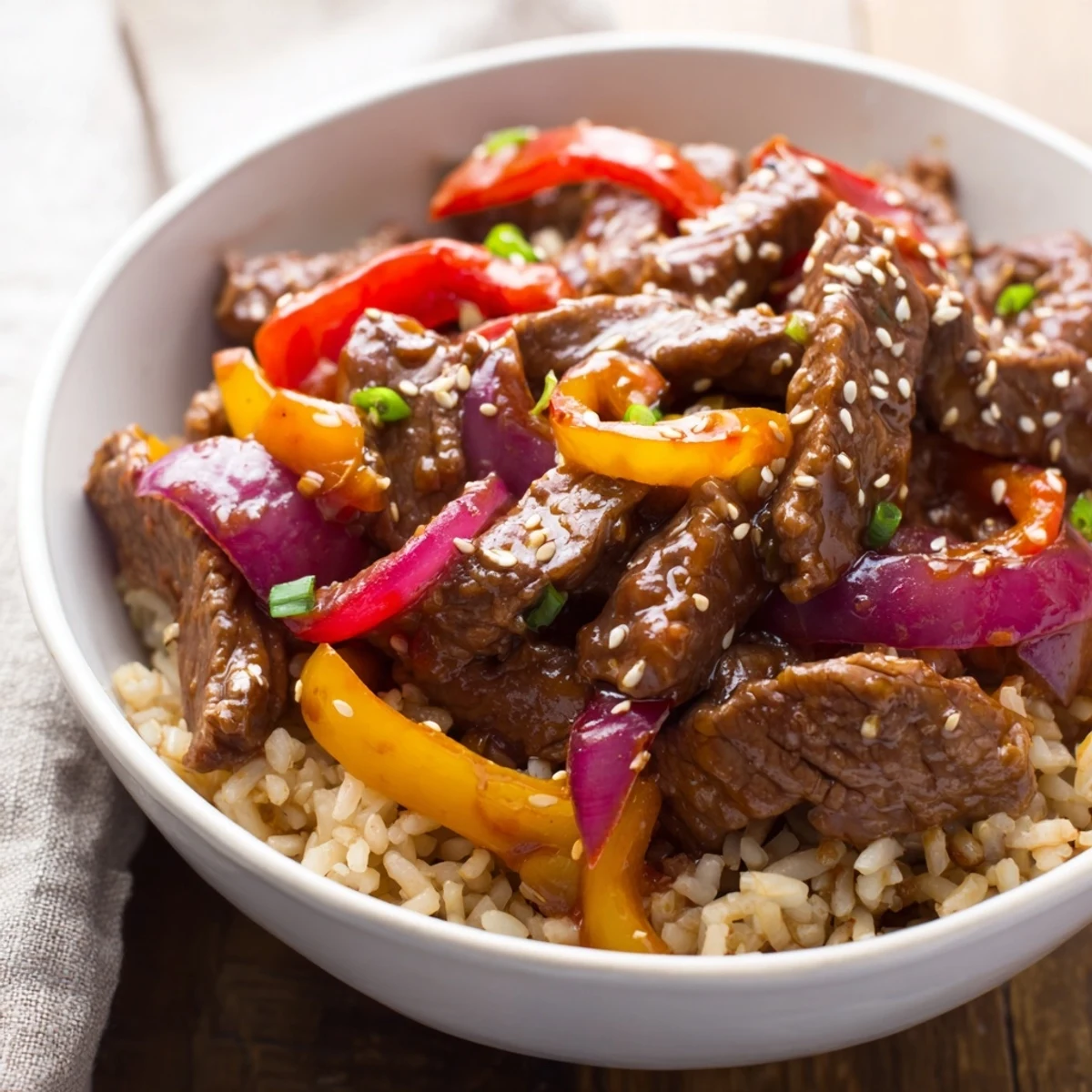 Vibrant beef and pepper rice bowl garnished with fresh cilantro and sesame seeds on a bed of nutty brown rice