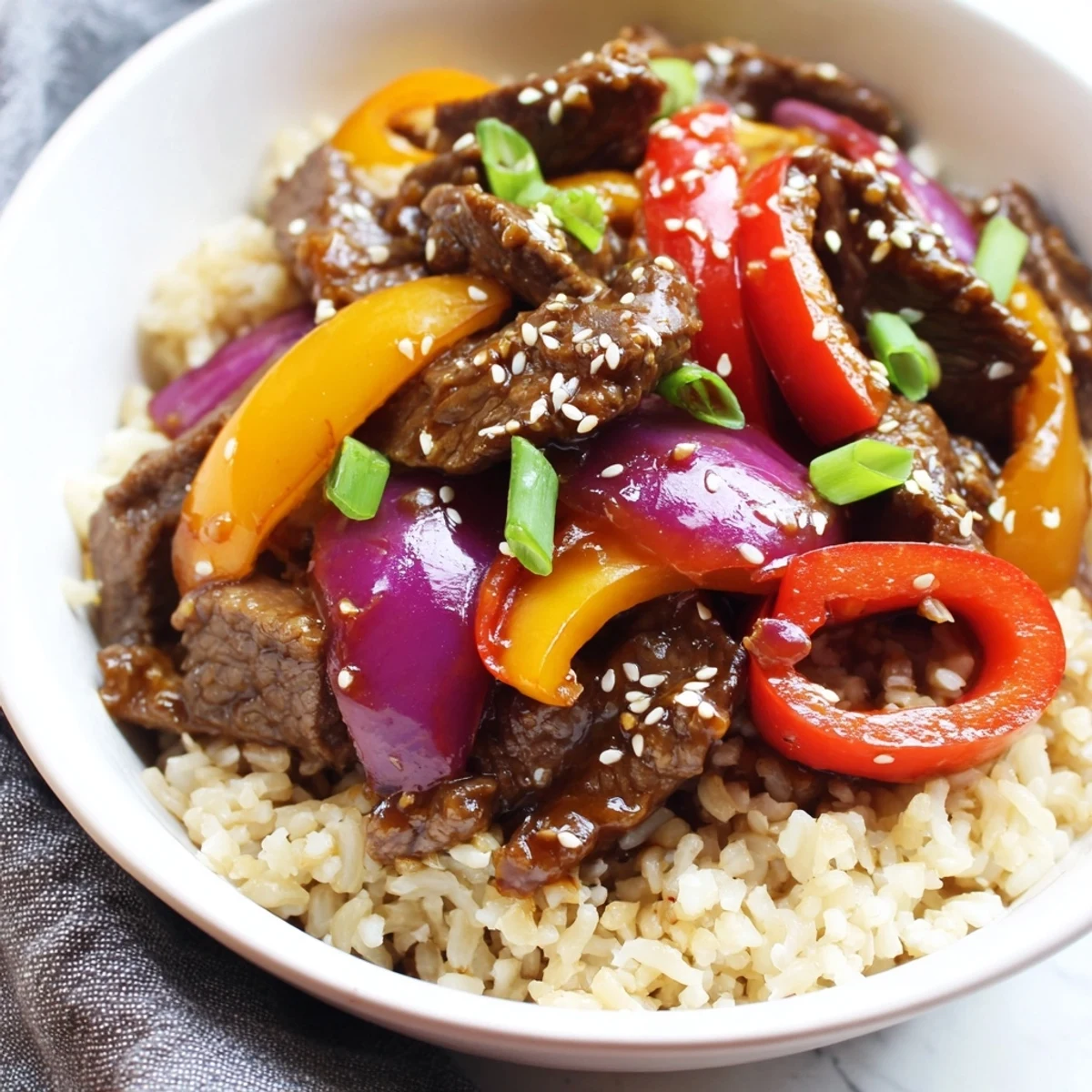 Savory healthy beef and pepper rice bowl showcasing sliced beef and crisp-tender vegetables coated in an Asian-inspired glaze