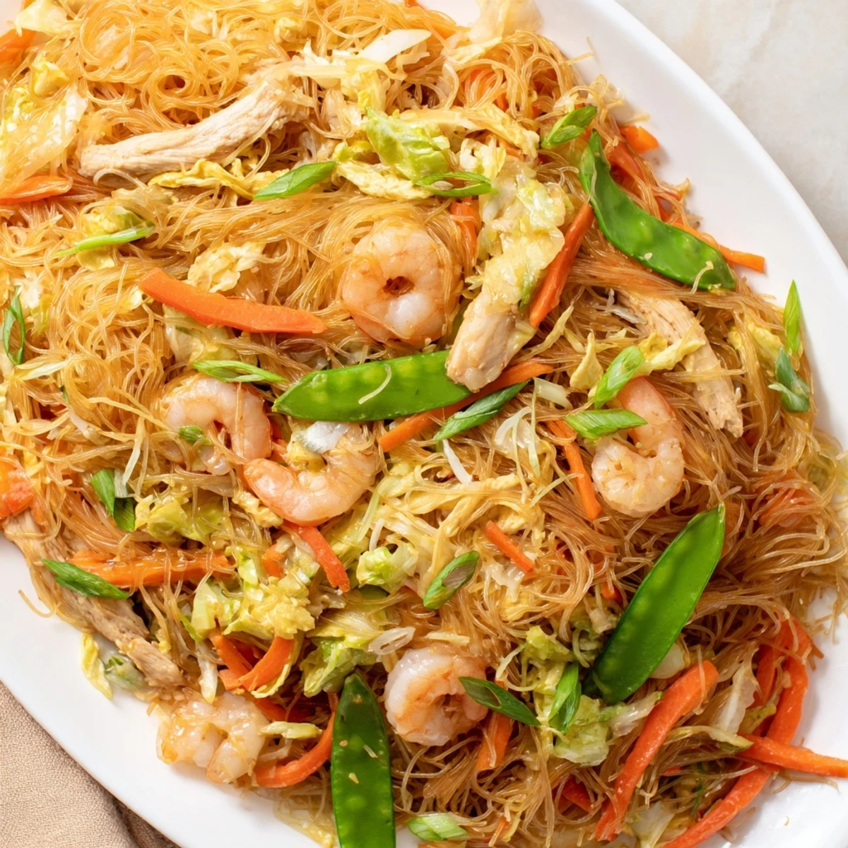 Golden Filipino Pancit Bihon topped with fresh scallions and served with calamansi wedges for a zesty, aromatic weeknight dinner.