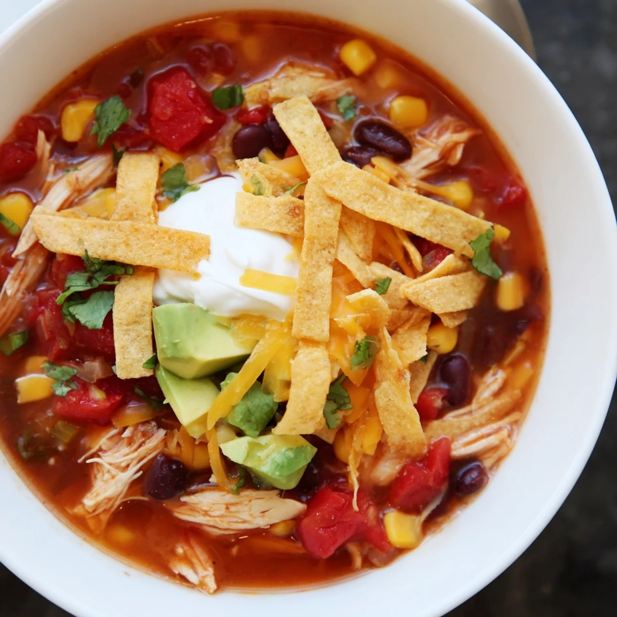 Vibrant Mexican-style chicken tortella soup served with lime wedges, sour cream, and crunchy tortilla garnish