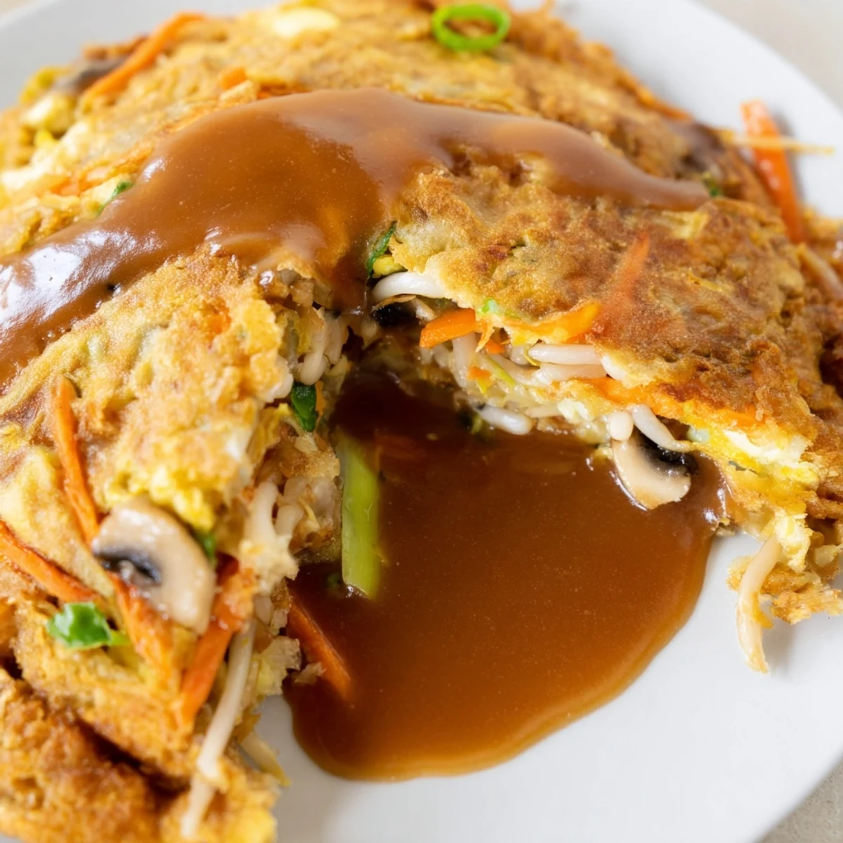 Chinese-style Egg Foo Young served hot with thick savory sauce over crispy edges