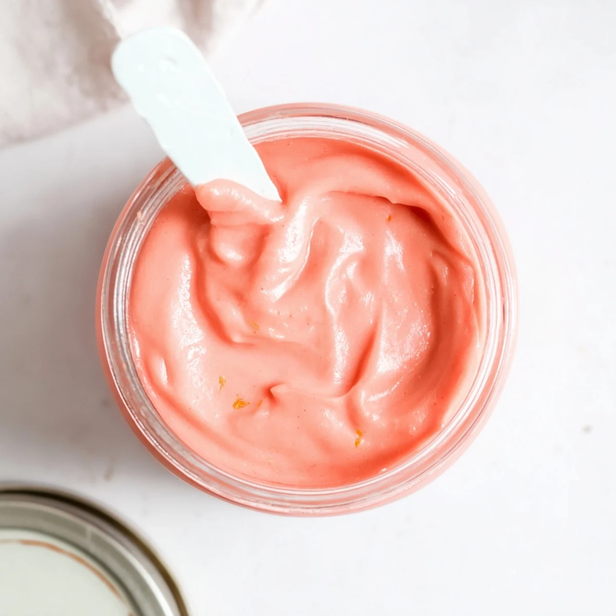 Vibrant pink lemon curd spread generously on a warm scone with fresh lemon zest garnish