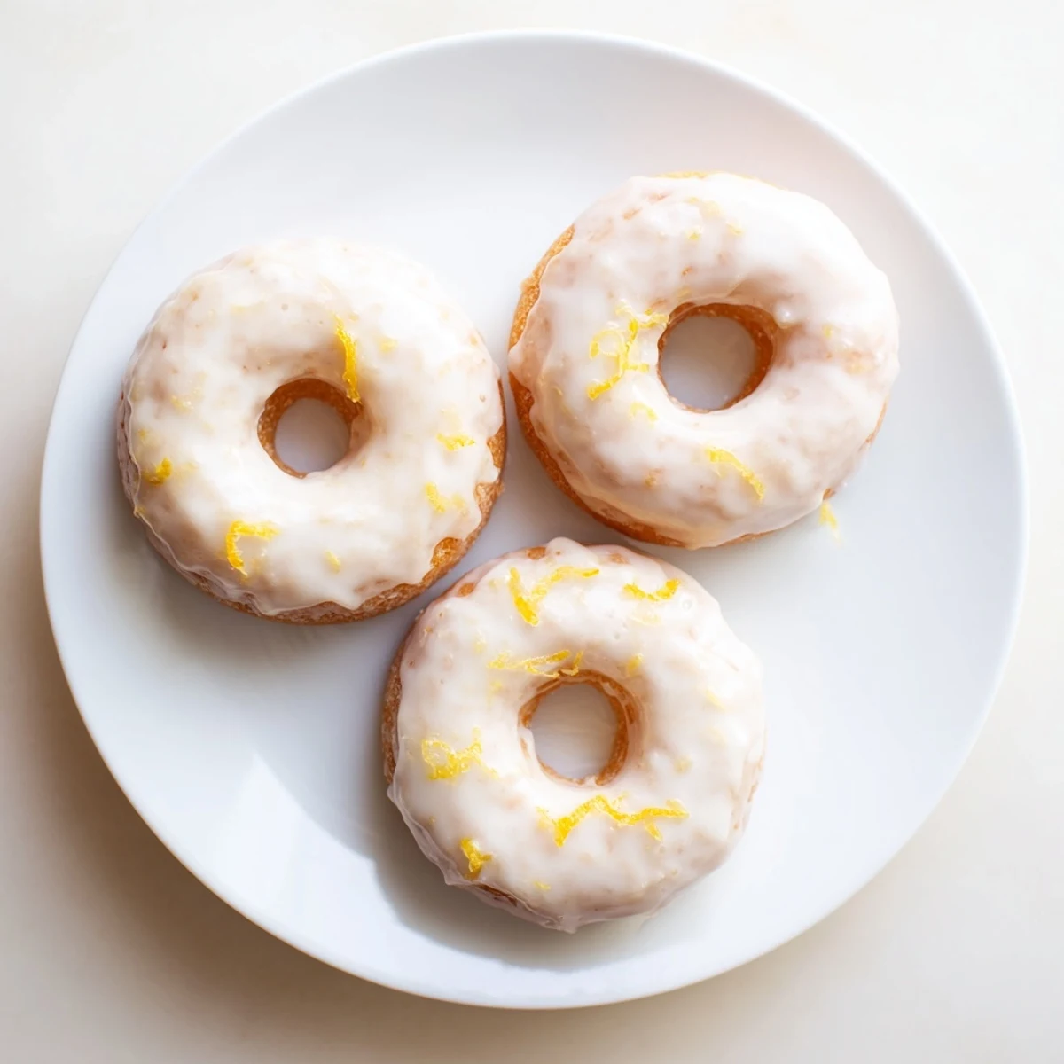 Soft baked lemon mochi donuts glistening with sweet lemony glaze on a white plate