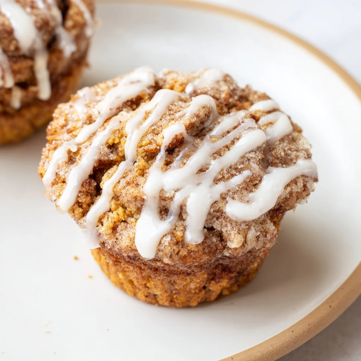 Fluffy cinnamon roll protein muffins cooling on a wire rack with glossy vanilla glaze