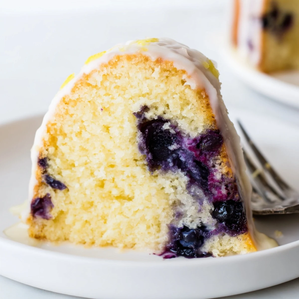 Golden lemon blueberry cake drizzled with tangy glaze and topped with fresh blueberries