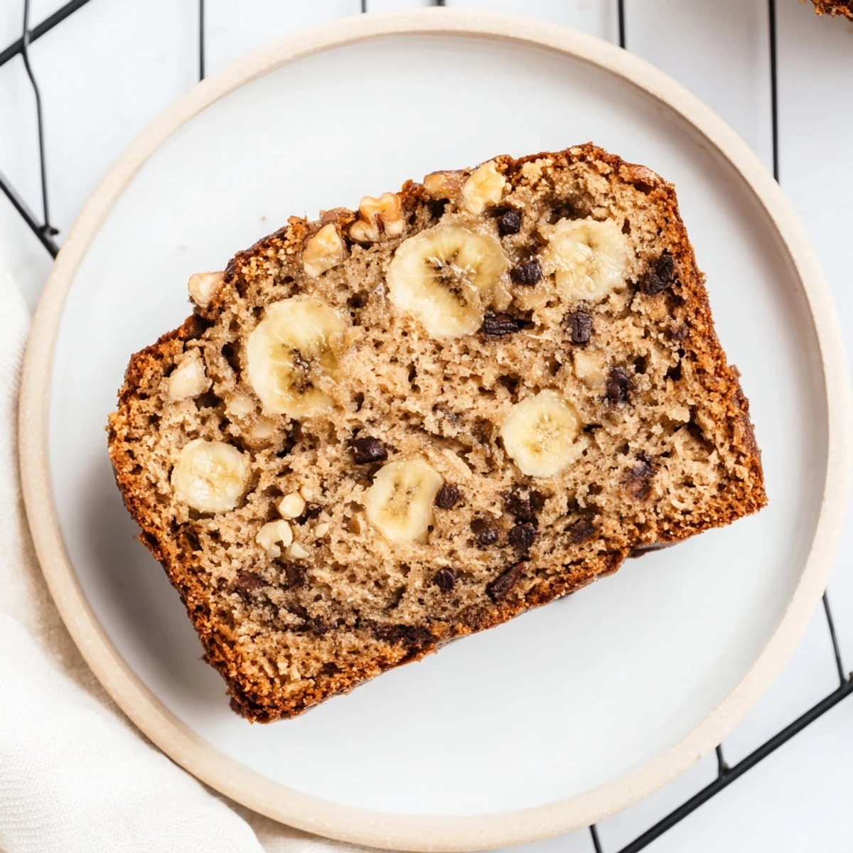 Golden brown moist banana bread loaf with a cracked top, sliced to reveal tender crumbs