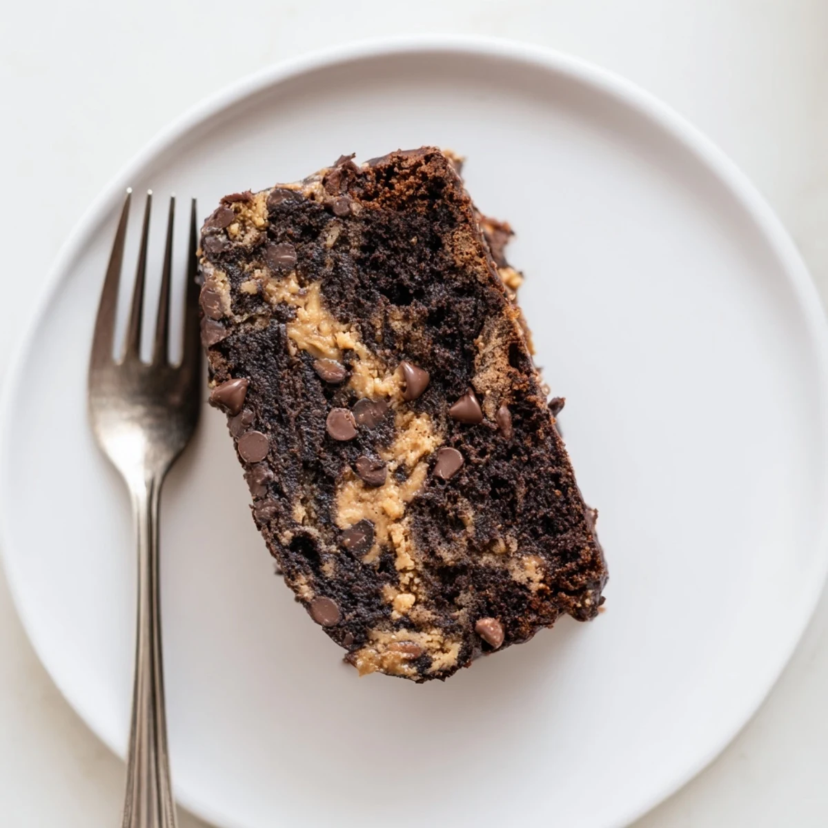 Golden slices of chocolate peanut butter banana bread with melty chips and swirled peanut butter topping on a wooden board