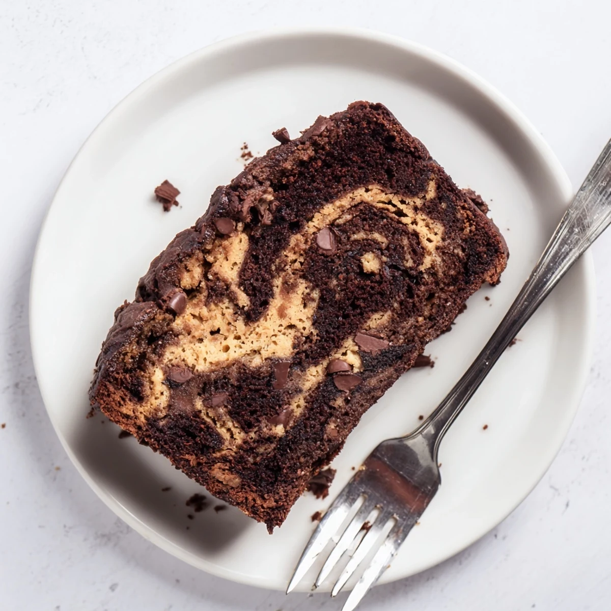 Freshly baked loaf of chocolate peanut butter banana bread cooling on wire rack with glossy peanut butter swirls