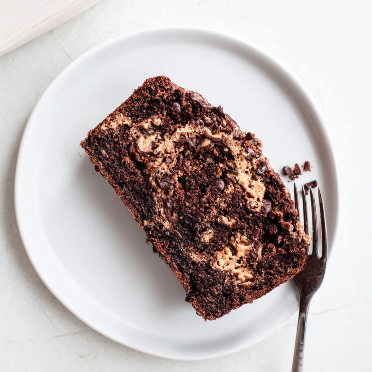 Thick slice of moist chocolate peanut butter banana bread revealing semi-sweet chocolate chips and dark cocoa marbled interior