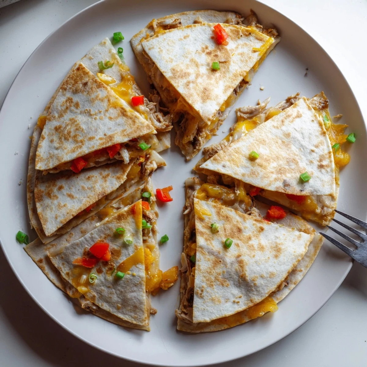 Easy baked chicken and cheese quesadillas cut into wedges served with fresh garnishes
