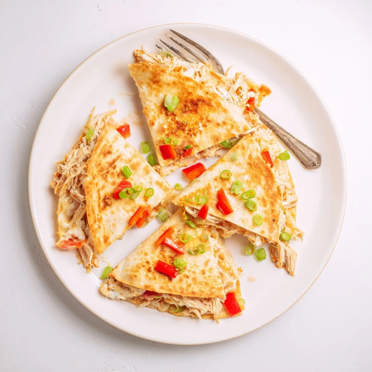 Crispy oven-baked quesadillas stuffed with seasoned shredded chicken and melted cheese on a platter