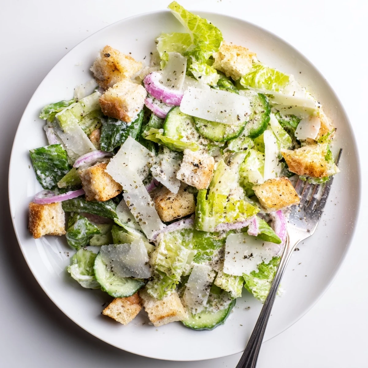 Colorful bowl of cucumber Caesar salad featuring sliced cucumbers, crunchy homemade croutons, and tangy homemade dressing