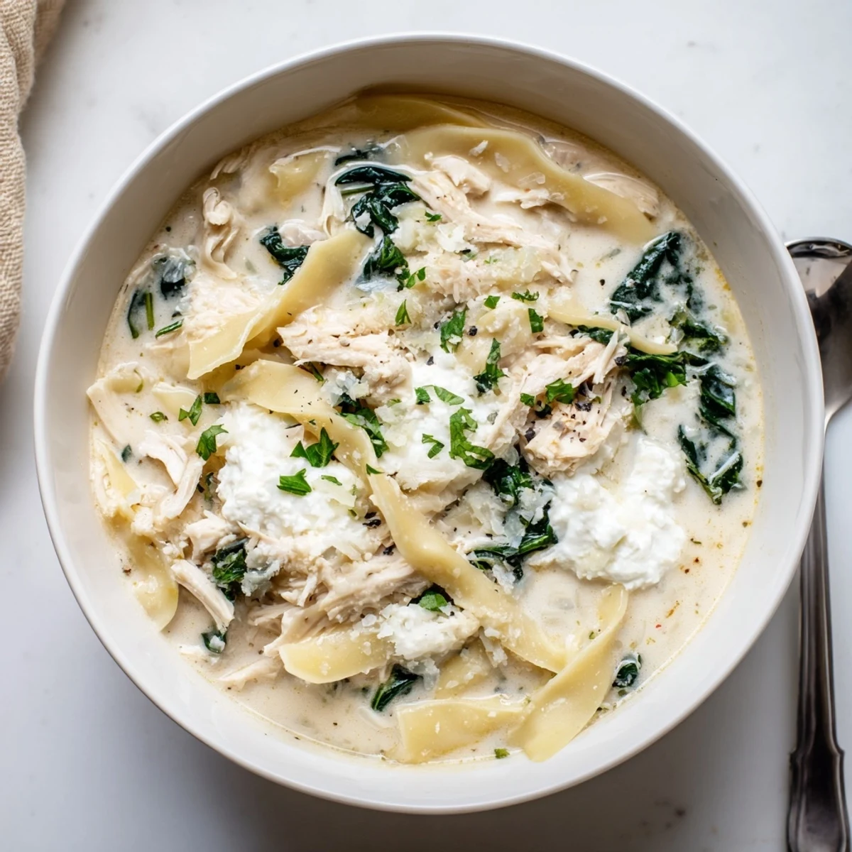 Creamy white lasagna soup with tender chicken noodles and melted mozzarella cheese in a savory Parmesan broth