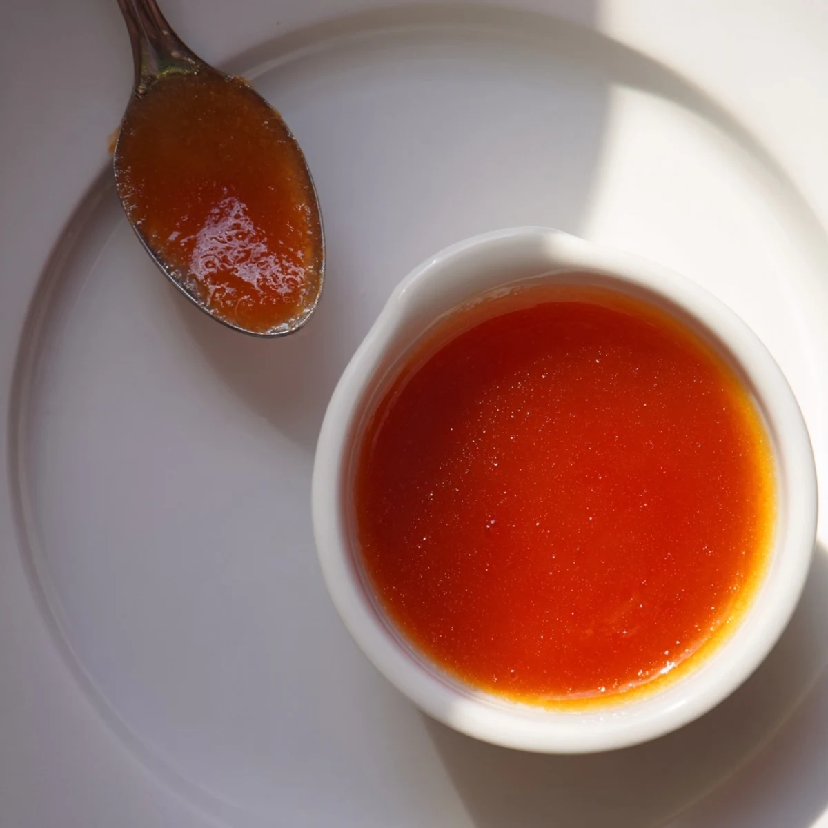 Golden orange McDonalds sweet and sour sauce in a small white ramekin for dipping