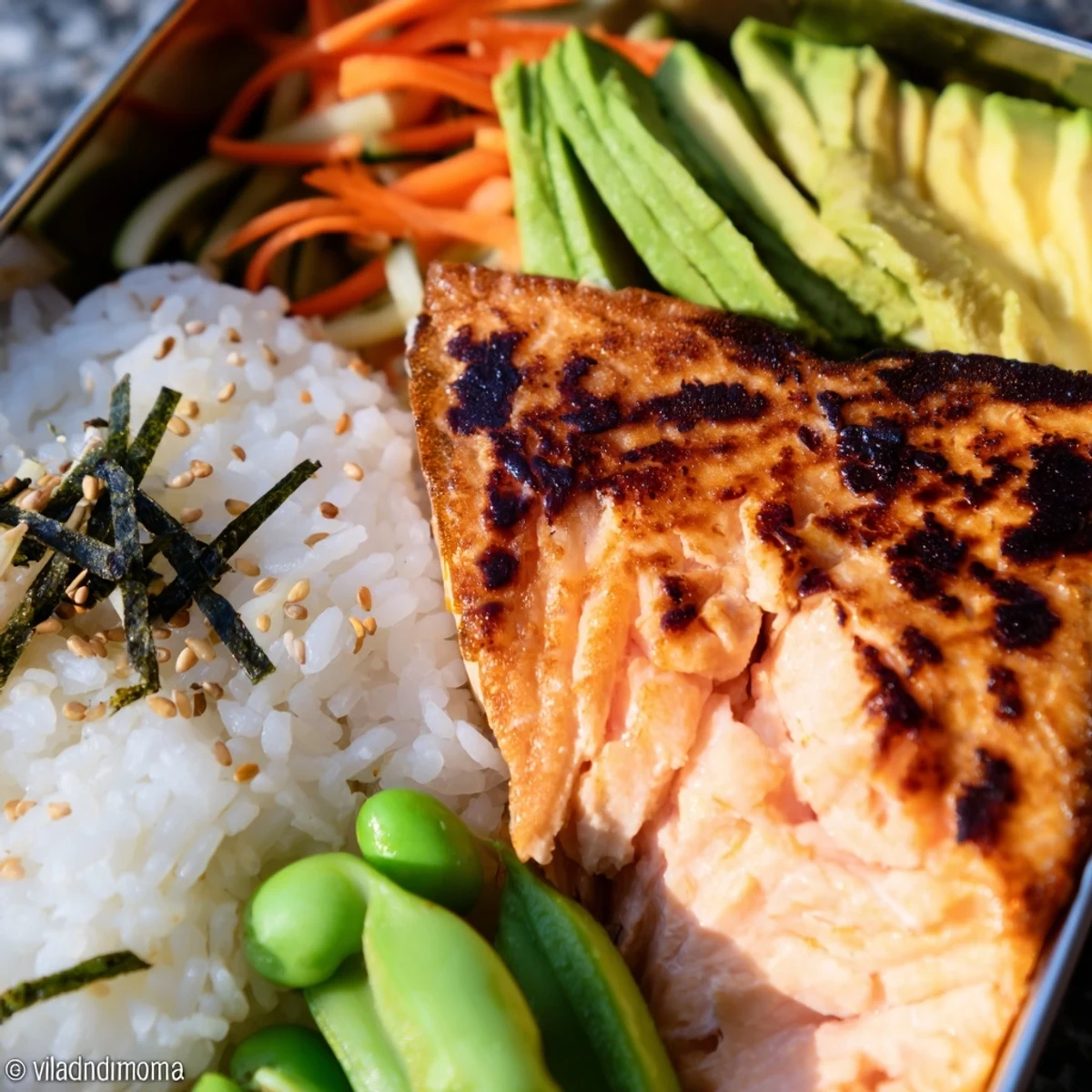 Healthy Japanese breakfast bento featuring tender fish, fluffy rice, pickled vegetables, and fresh fruit in a divided container