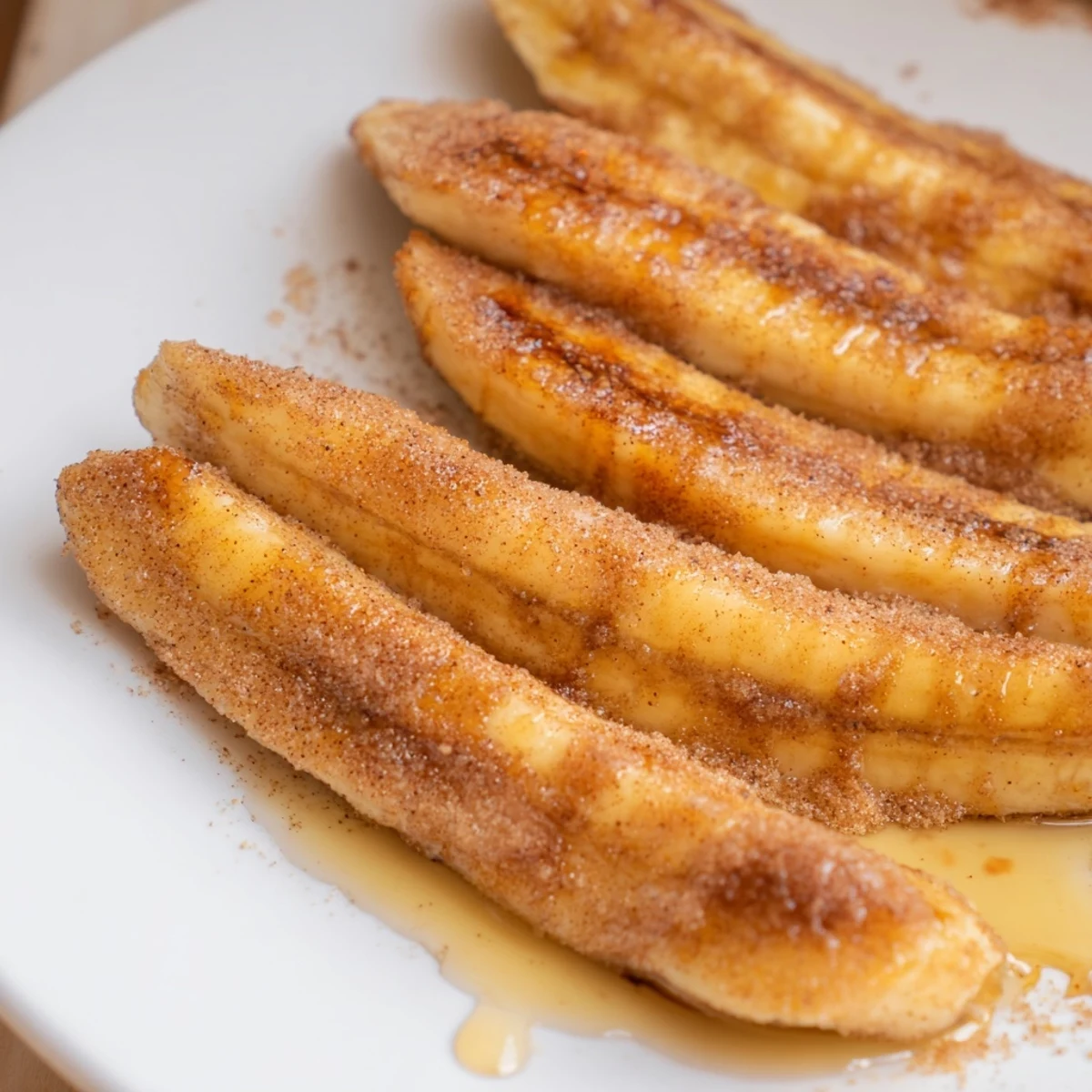 Sliced bananas sizzling in skillet with cinnamon sugar for a sweet dessert topping