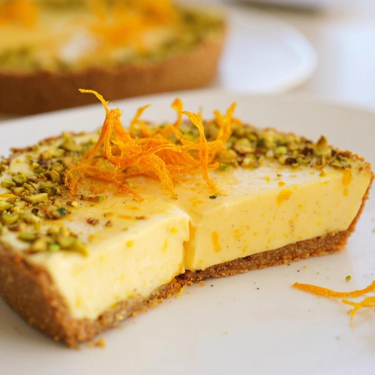 Orange cardamom tart with creamy citrus filling nestled in a golden pistachio crust
