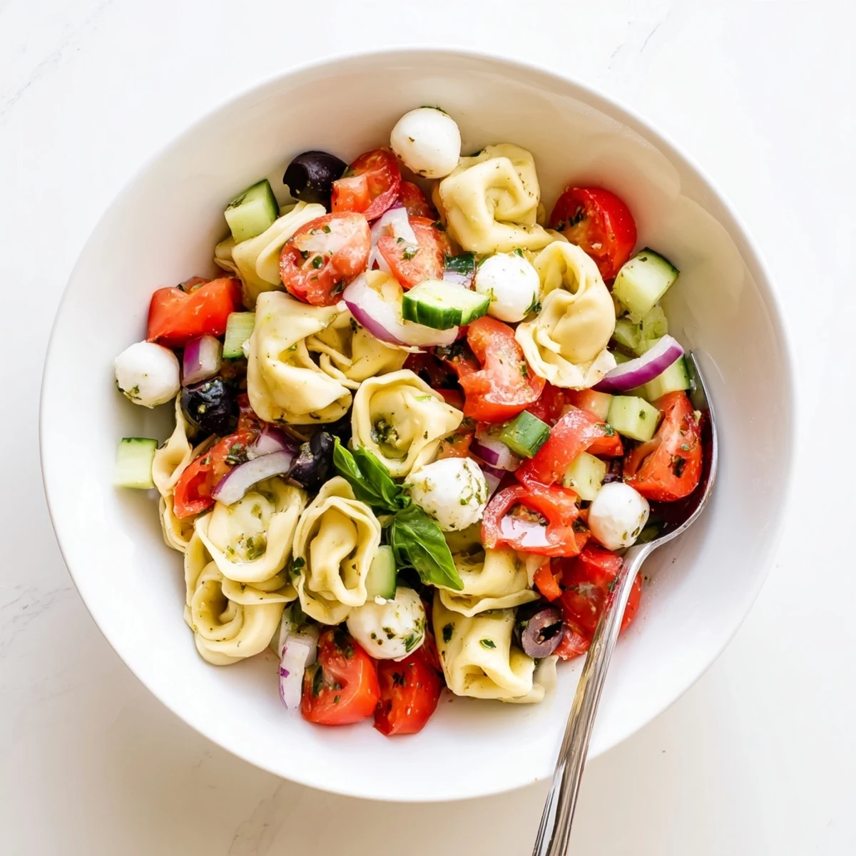 Colorful tortellini pasta salad with cherry tomatoes, cucumber, and zesty Italian dressing in a serving bowl