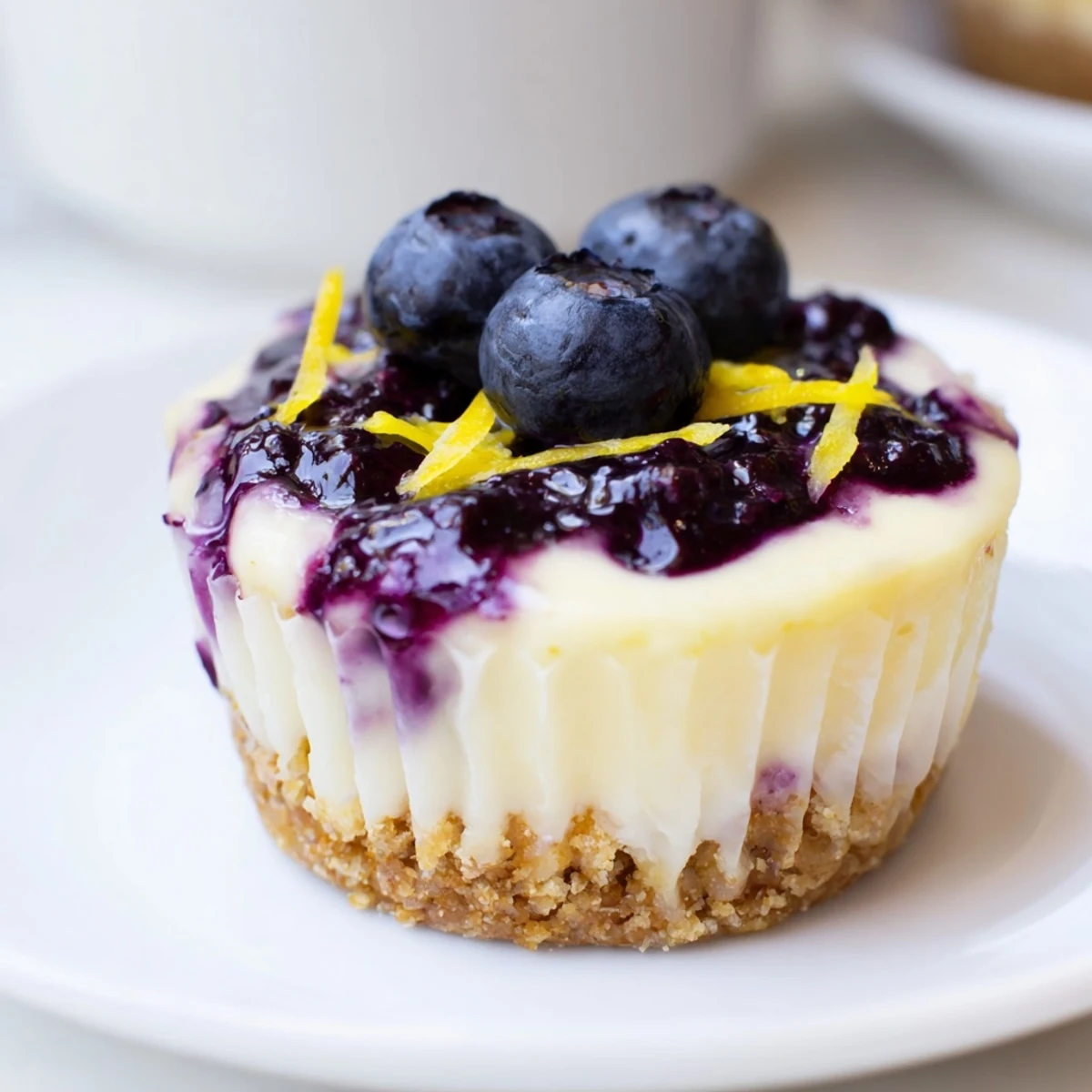 Golden mini lemon blueberry cheesecakes topped with glossy berry compote on a rustic plate