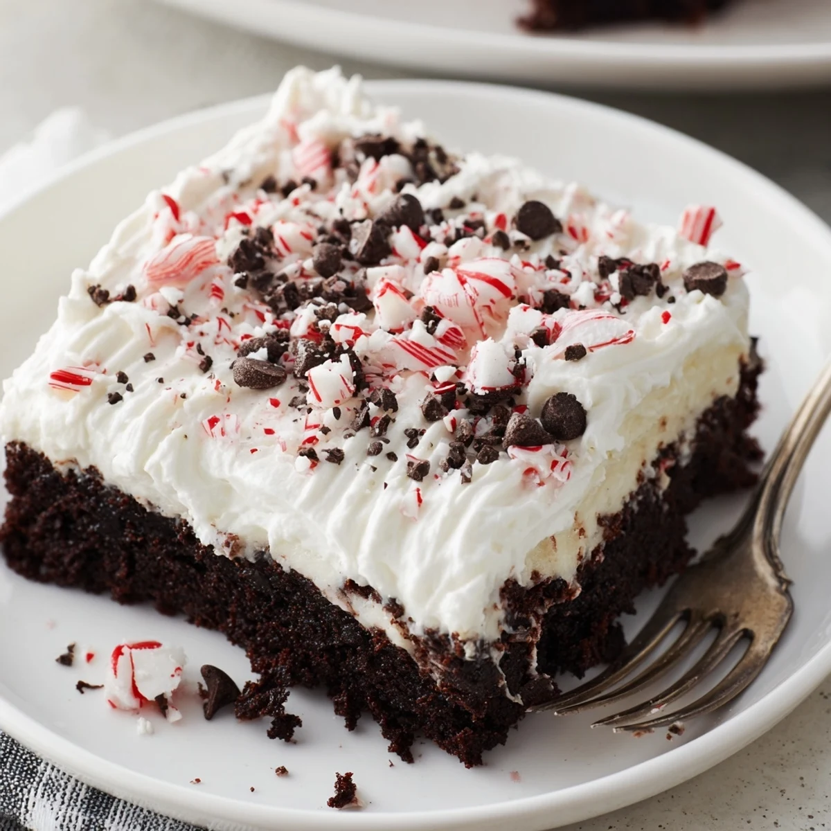 Peppermint Poke Cake chilled with fluffy whipped topping and crunchy candy.