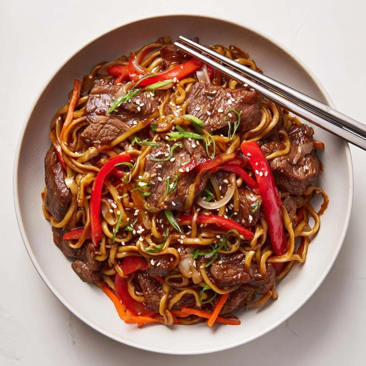 Sticky Beef Noodles glistening with glossy sauce, tender beef, sesame garnish  