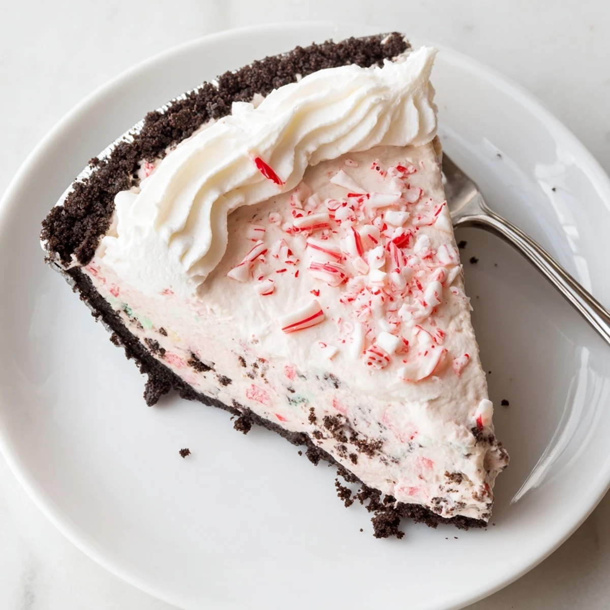 Festive Candy Cane Pie served with whipped cream, crunchy peppermint pieces