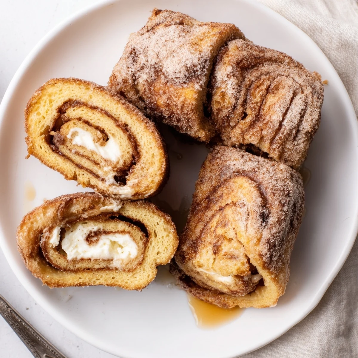 Buttery skillet-seared Cinnamon Roll French Toast Roll Ups served with maple syrup