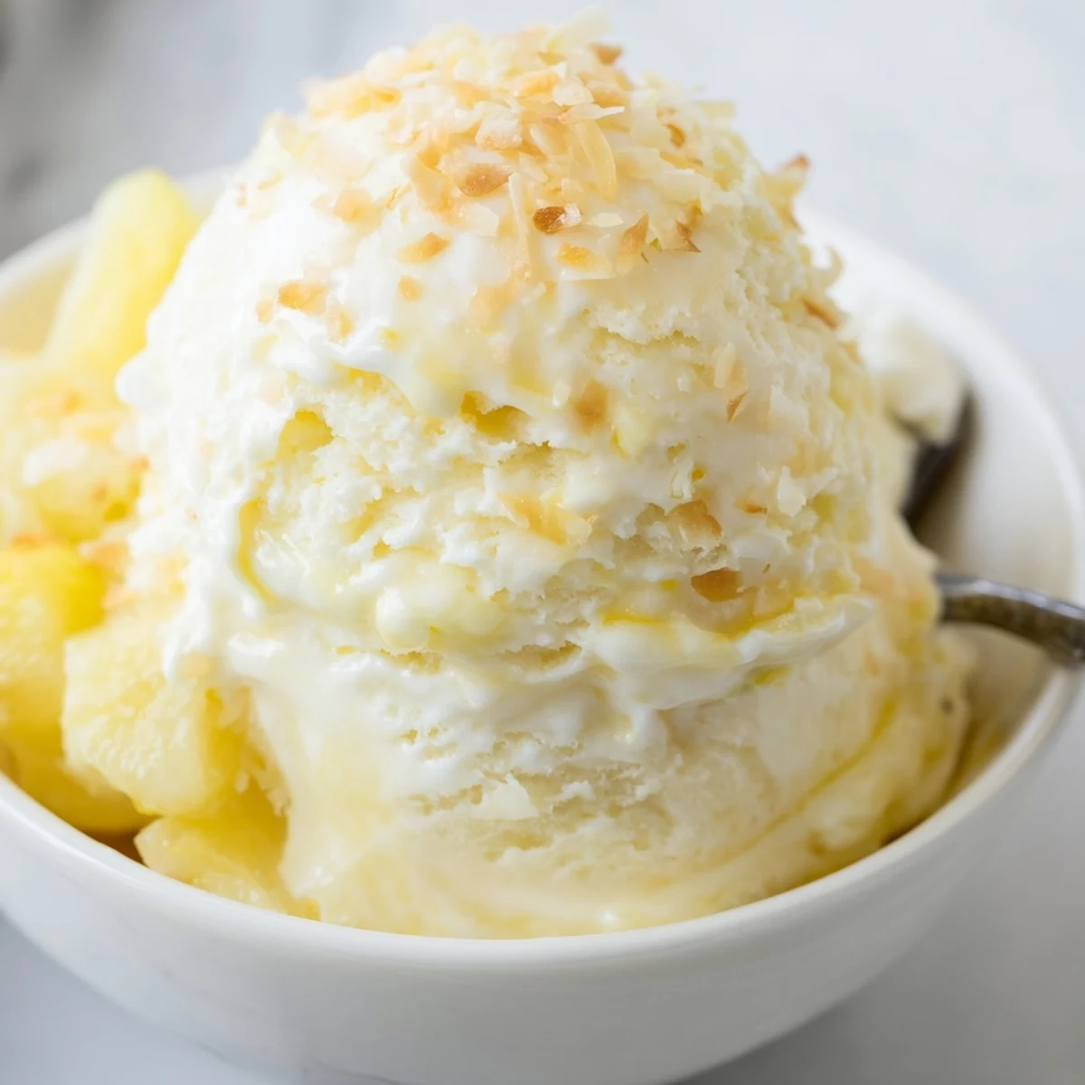 Creamy Pineapple Ice Cream swirled in a bowl, fragrant, velvety summer dessert  