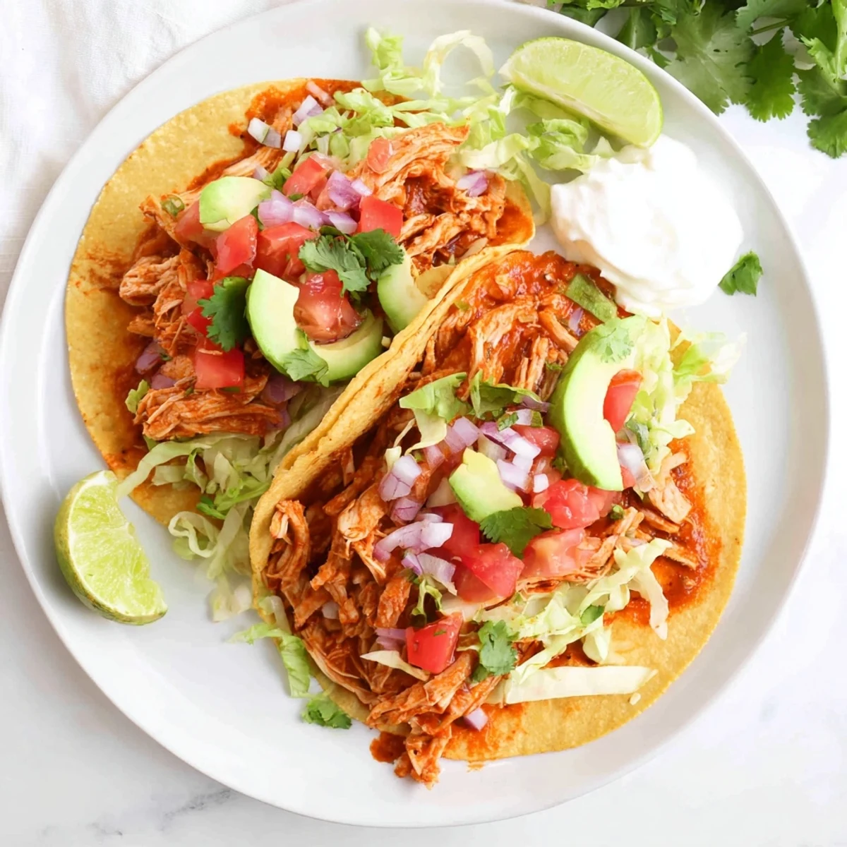 Golden slow cooker chicken tacos topped with fresh lettuce, cheese, and creamy avocado