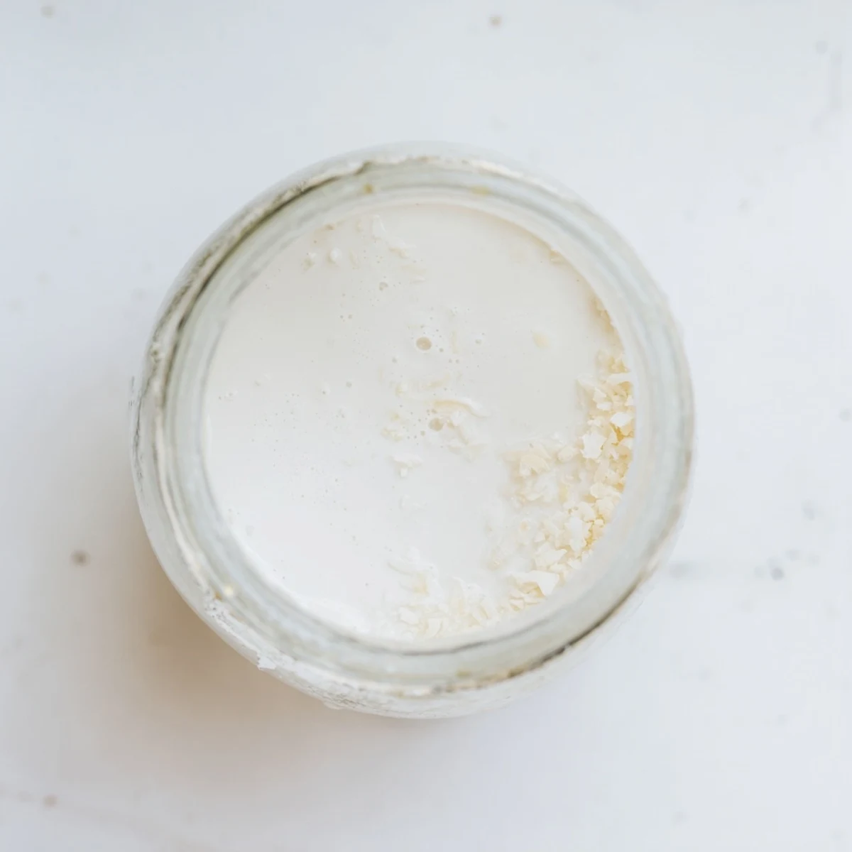 Creamy homemade coconut milk recipe poured into a glass jar with rich white texture