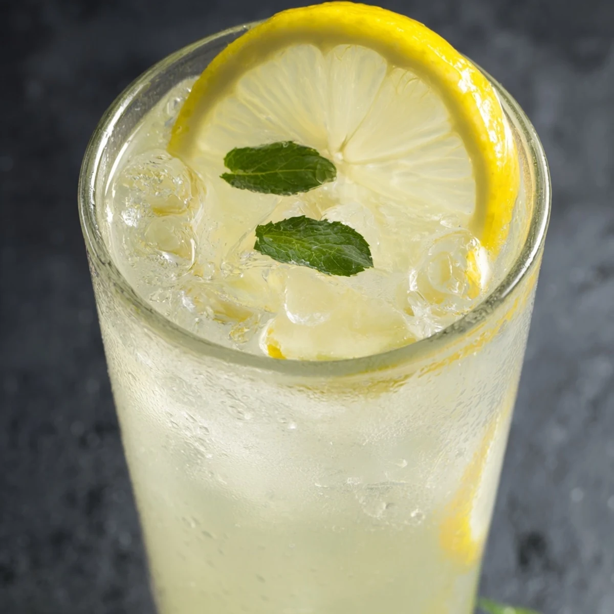 Easy homemade lemonade recipe in a clear pitcher topped with floating lemon wheels and fresh mint leaves