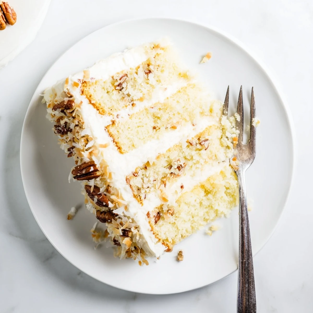 Golden slice of quick Italian cream cake topped with toasted pecans and shredded coconut