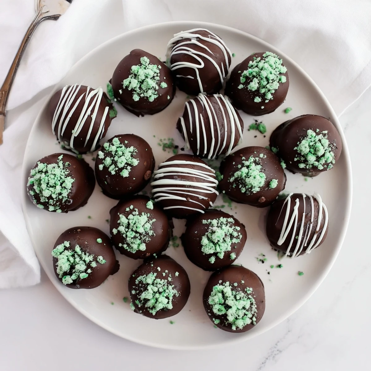 Rich chocolate-dipped mint Oreo truffles on a white serving plate ready for parties