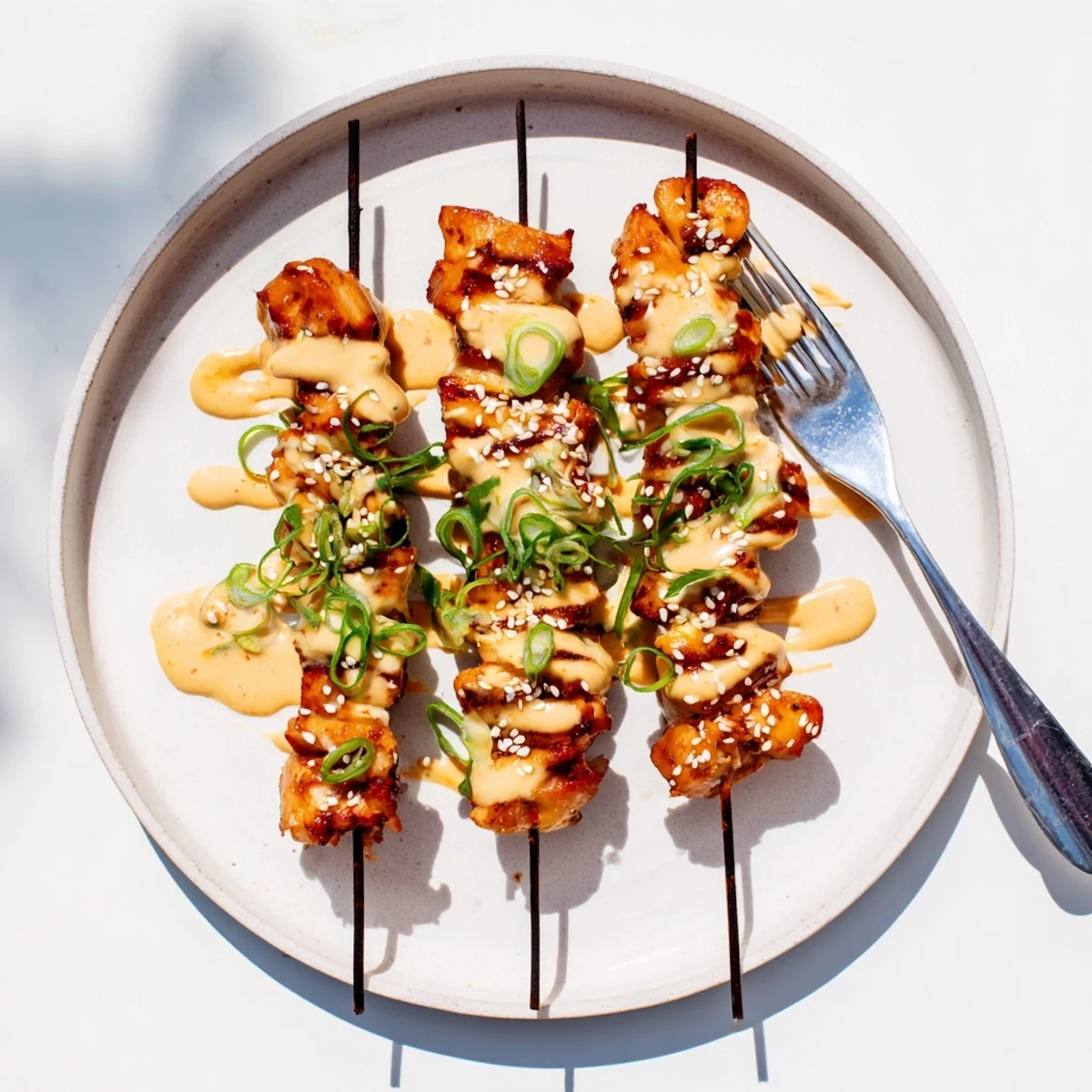 Golden grilled Bang Bang Chicken skewers drizzled with creamy spicy sauce and sesame seeds