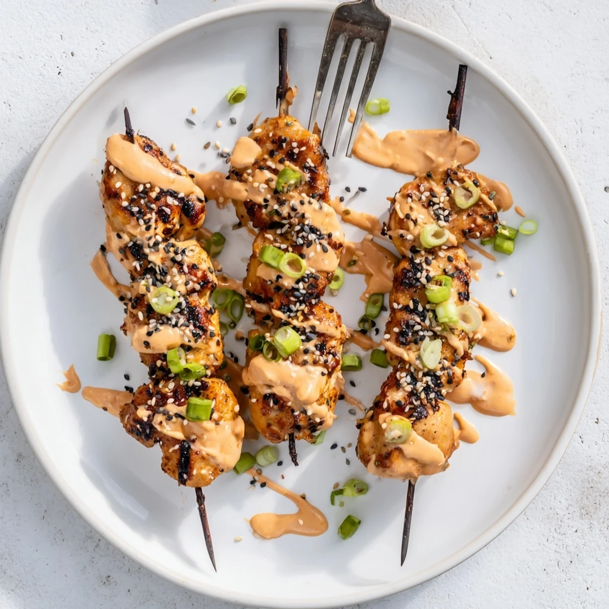 Charred Bang Bang Chicken skewers brushed with sweet chili Sriracha sauce ready for serving