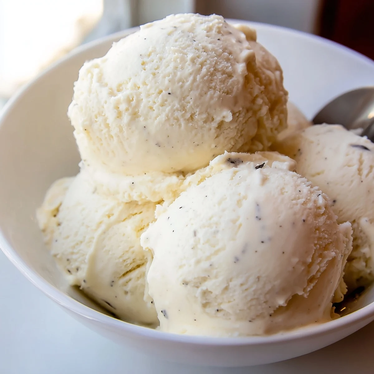 Creamy vanilla ice cream recipe scooped into vintage glass dish with wafer cookie garnish