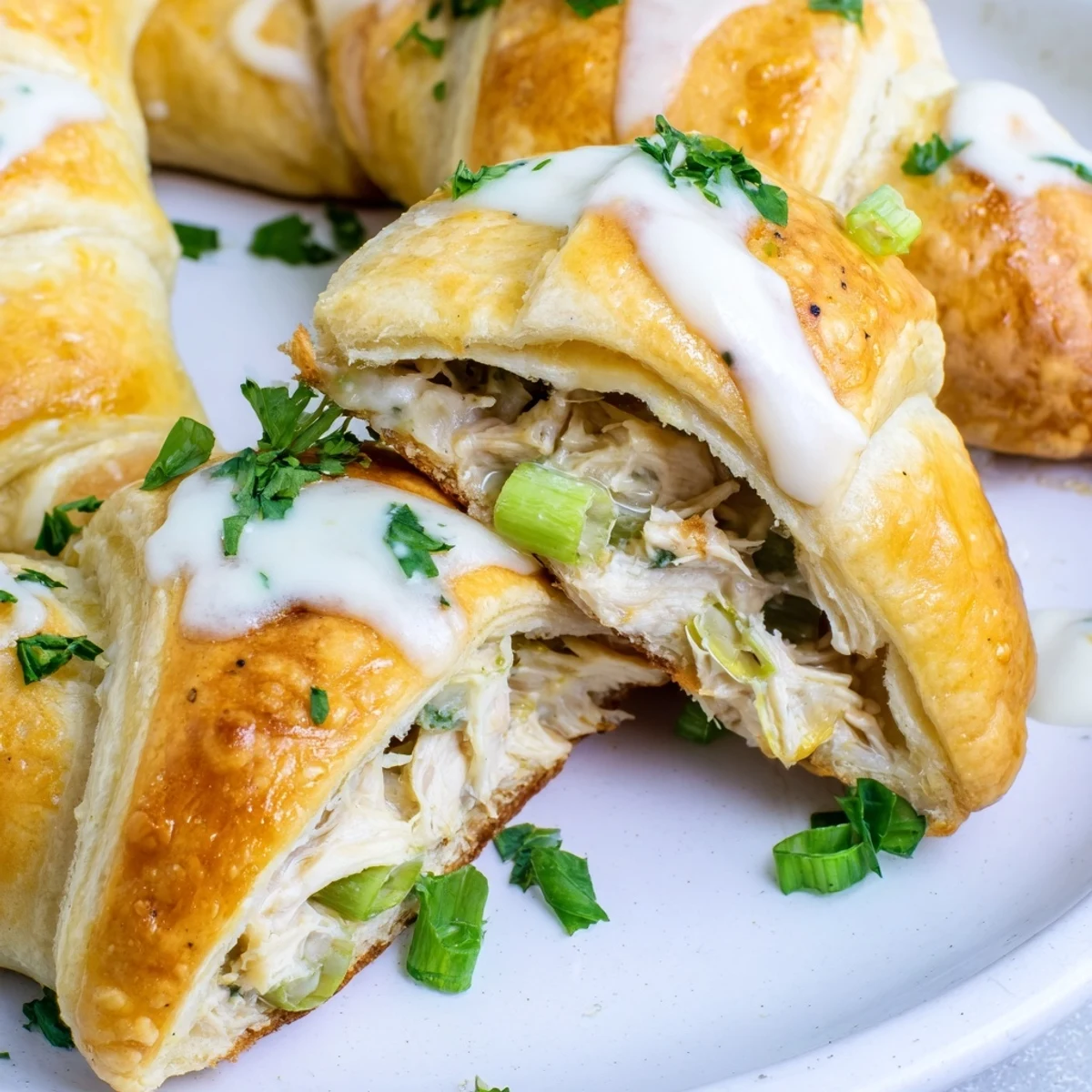 Golden baked chicken pillows with creamy parmesan sauce drizzled over flaky crescent dough
