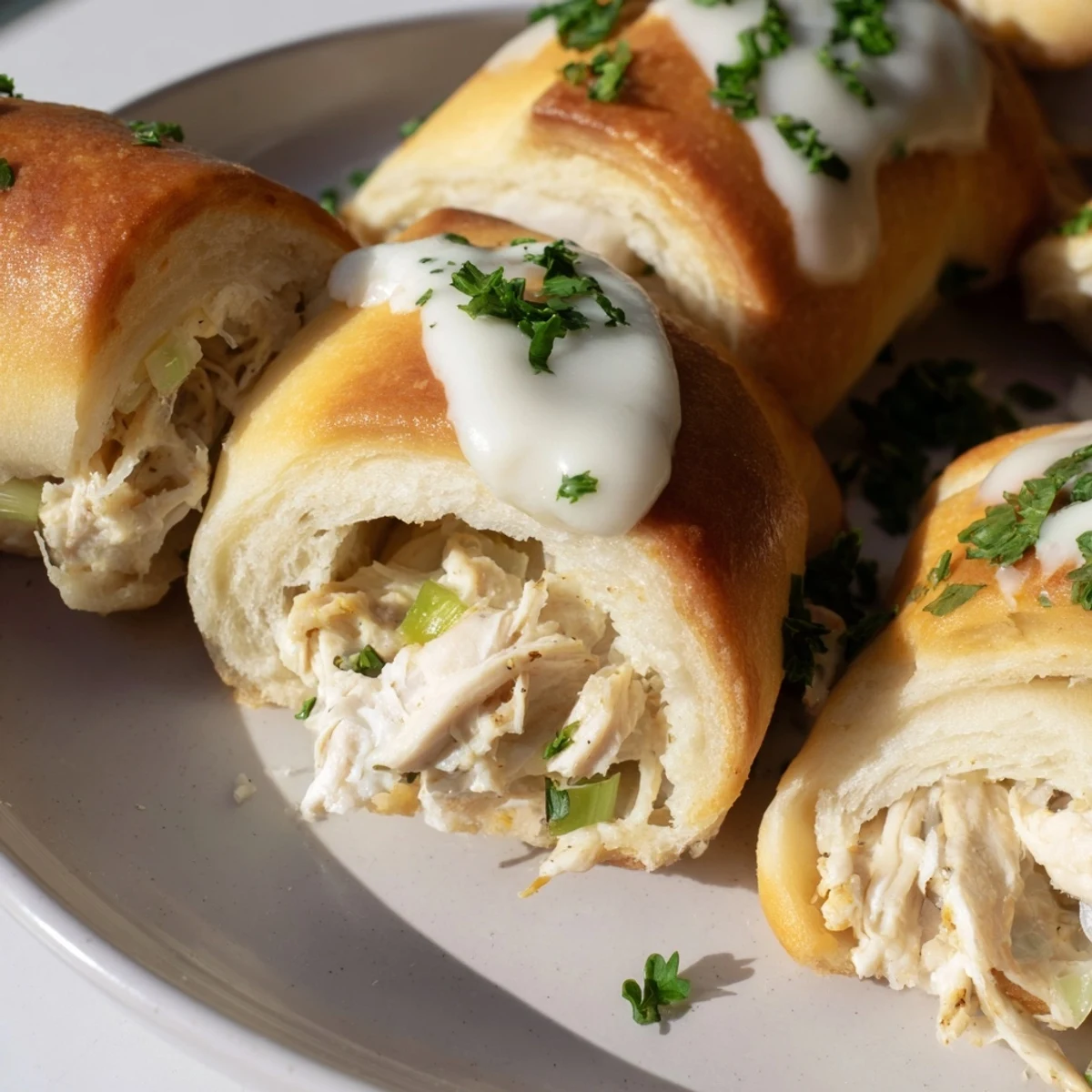 Tender chicken wrapped in crescent rolls topped with rich white parmesan sauce and parsley