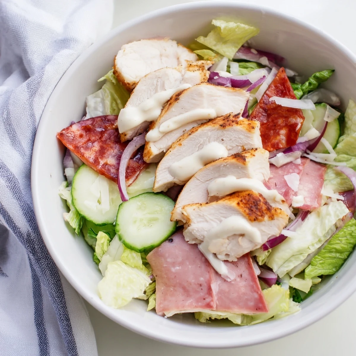 Hearty Italian Grinder Chicken Salad topped with grilled chicken, salami, provolone, and fresh crisp vegetables.