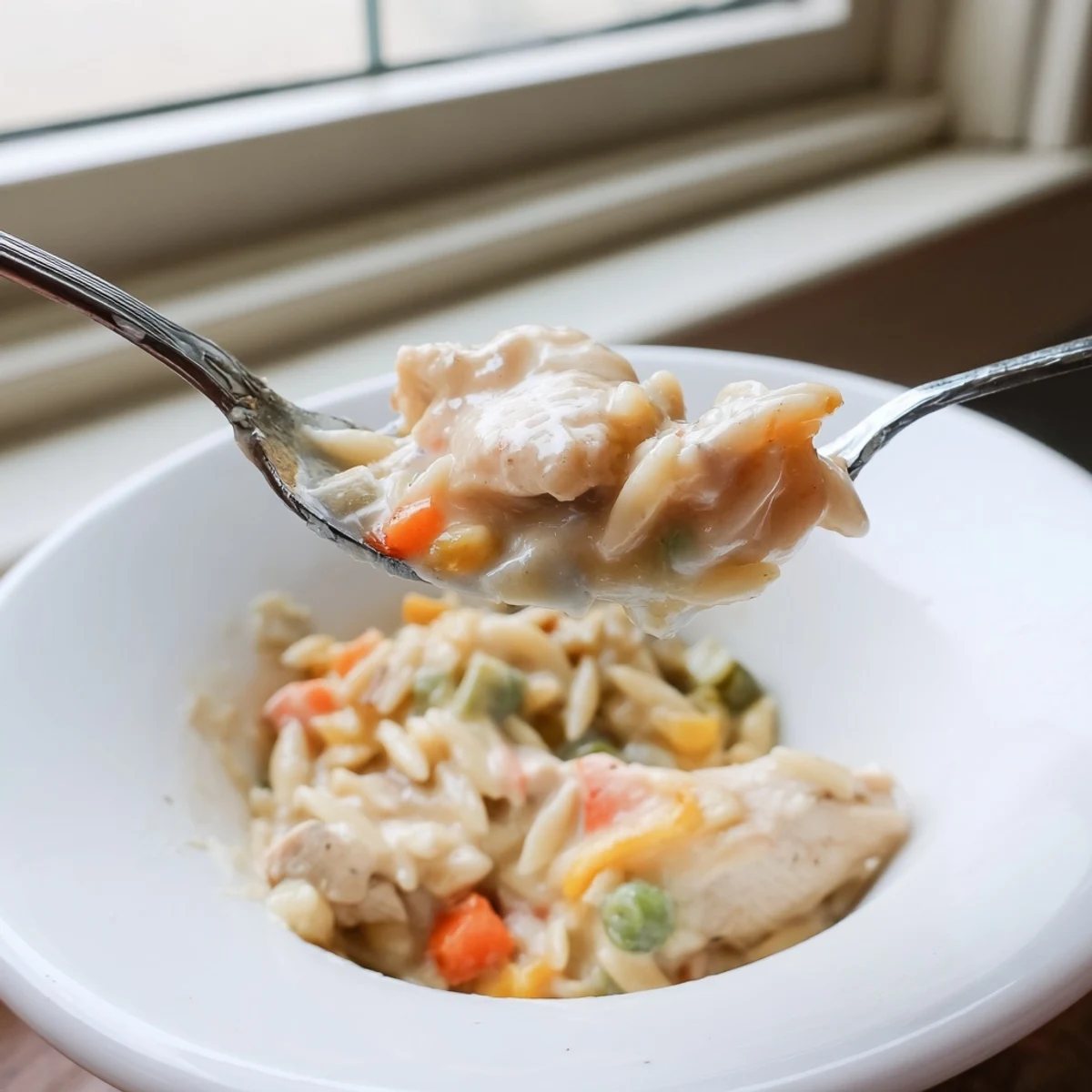 A comforting bowl of creamy chicken pot pie orzo garnished with grated parmesan cheese.